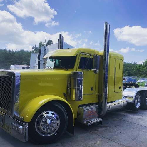 A yellow semi truck is parked on the side of the road.