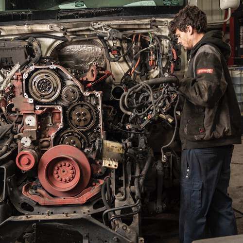 A man is working on the engine of a truck.