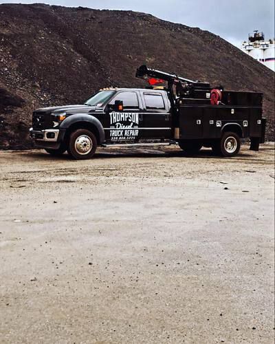 A black tow truck is parked on the side of the road.