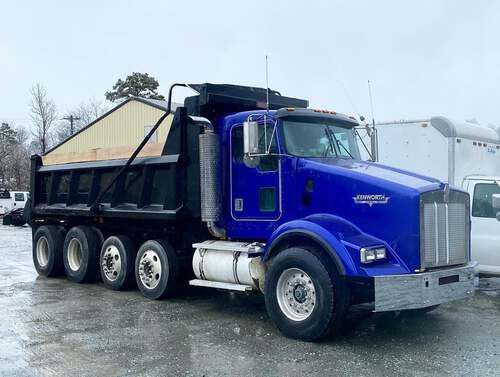A blue dump truck is parked in a parking lot.