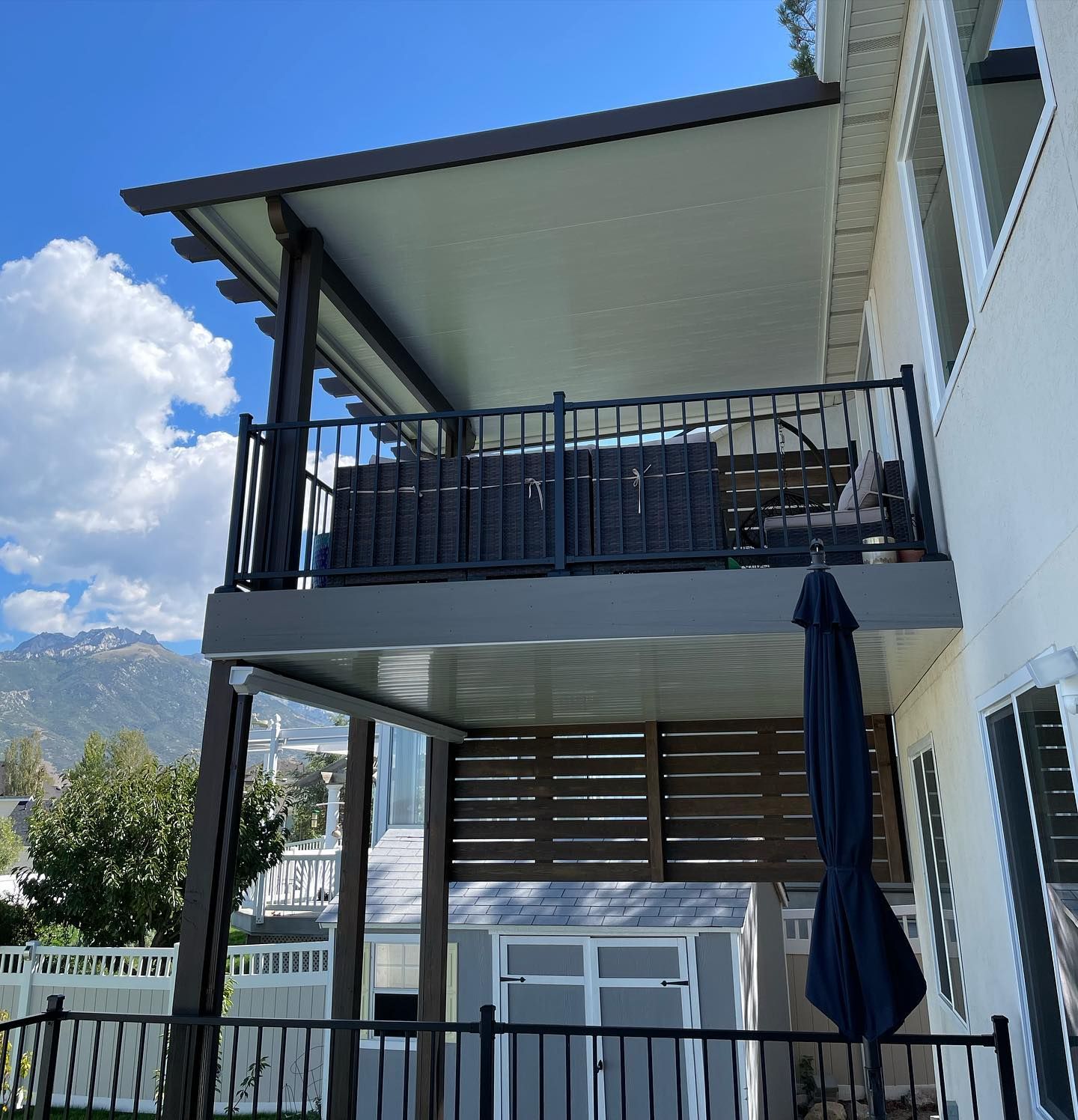 A white house with a balcony and a blue umbrella