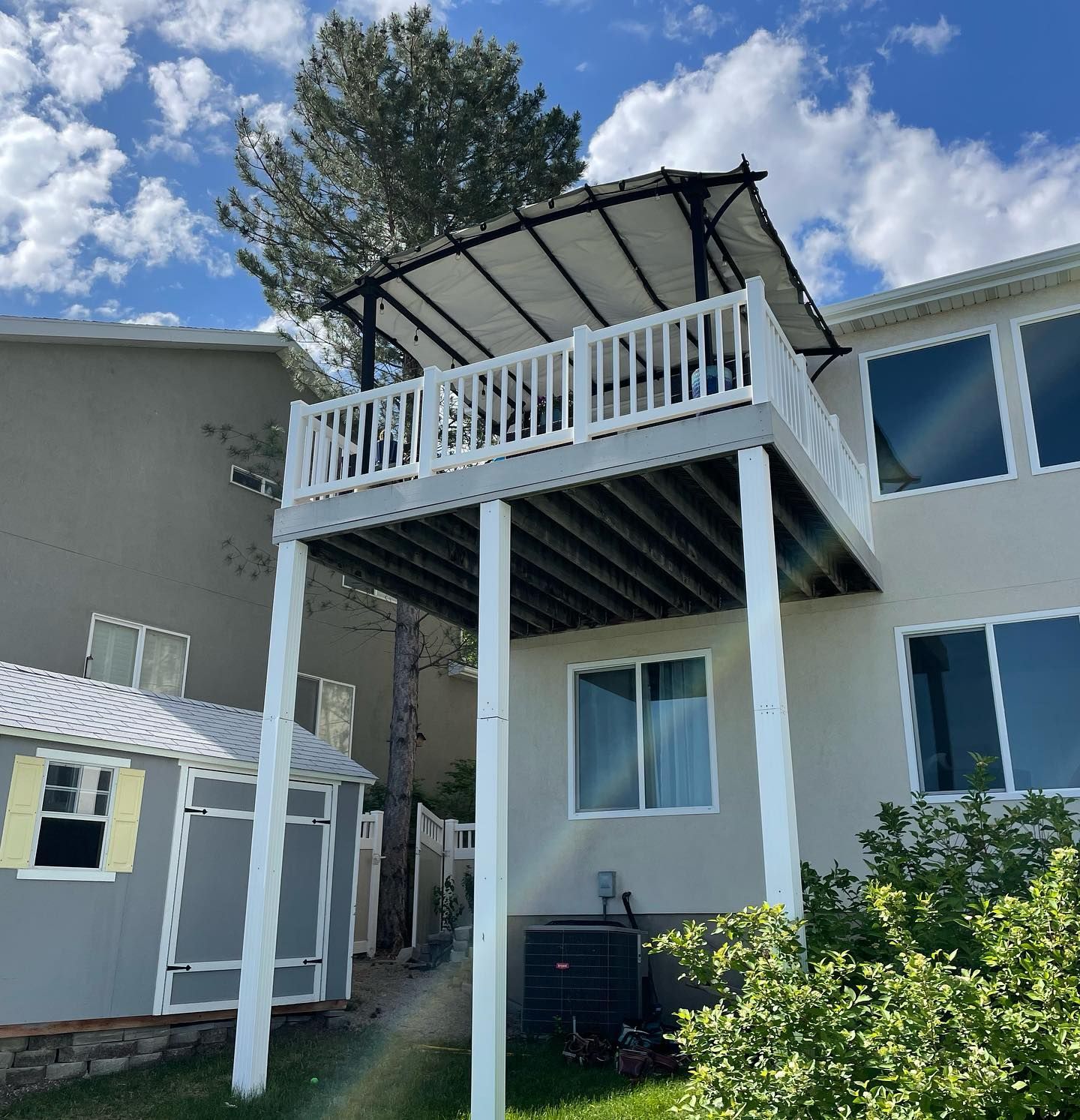 A house with a large deck and a shed in front of it