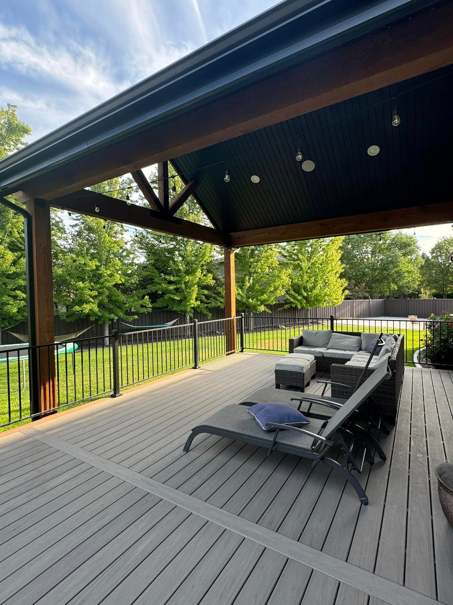 A patio with a couch and chairs under a canopy.