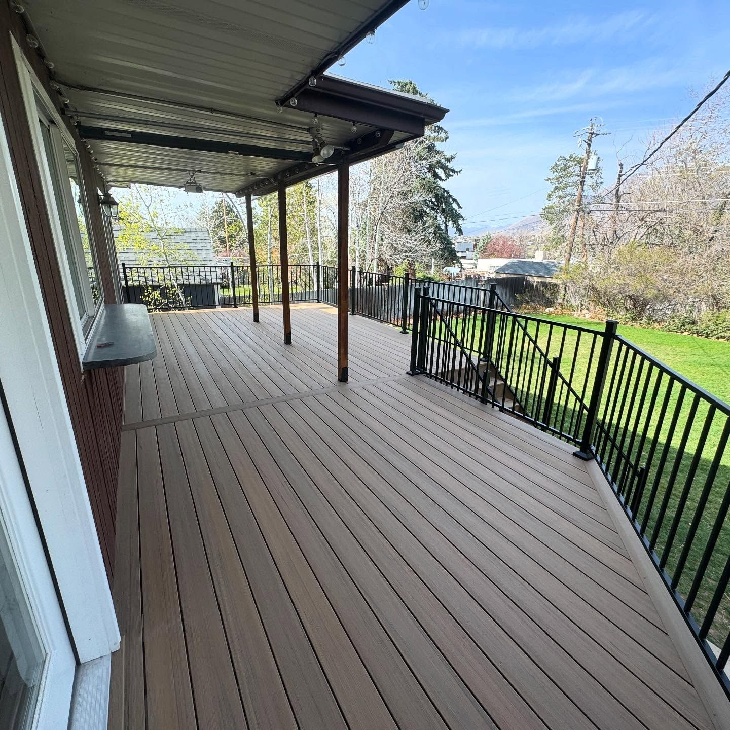 A large wooden deck with a metal railing and a covered area.