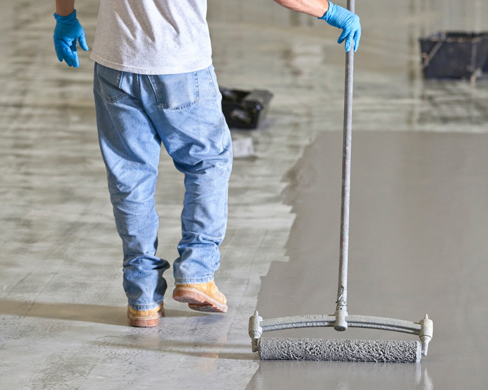 worker smoothing out epoxy coating on a concrete slab