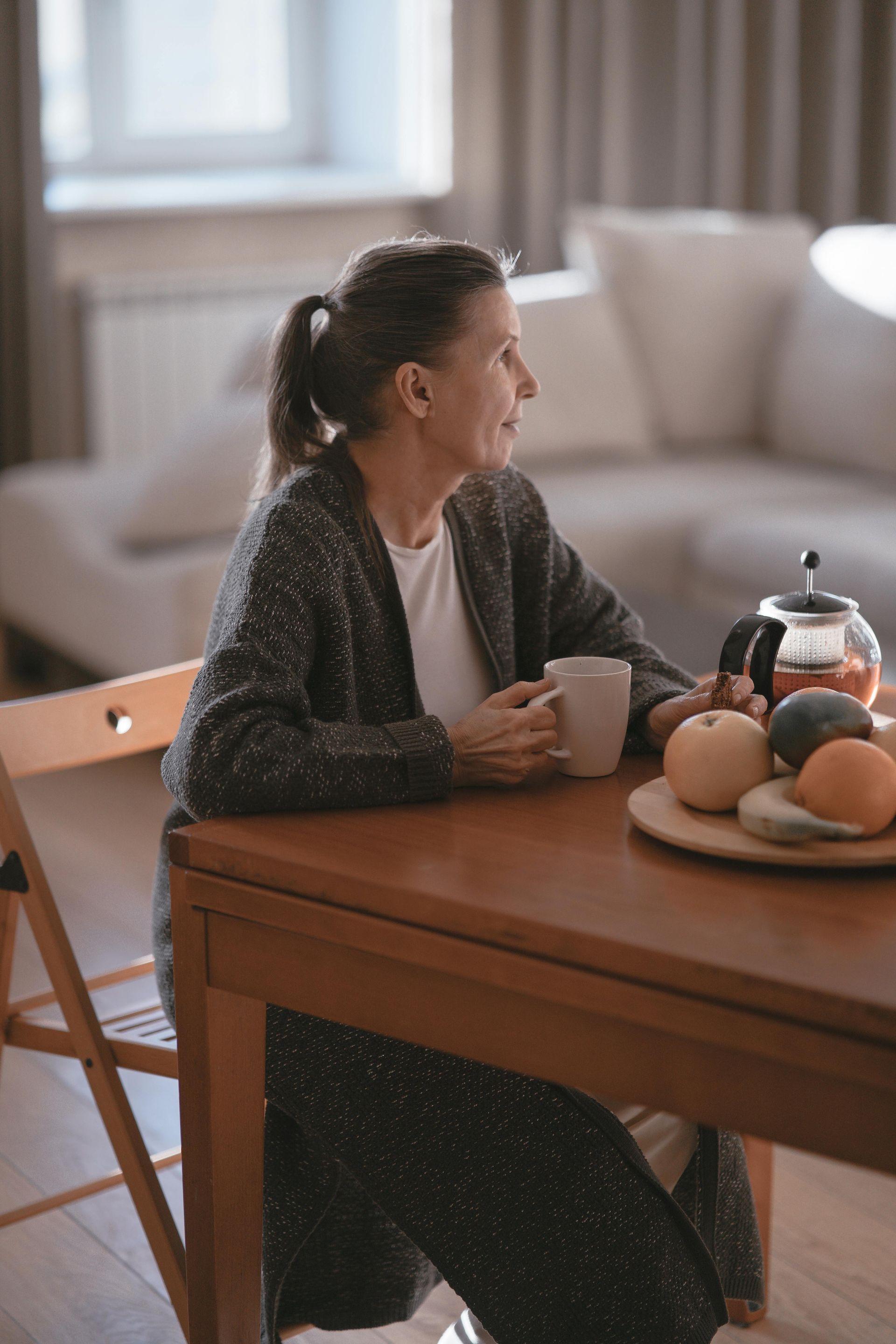 A woman is sitting at a table holding a cup of coffee.