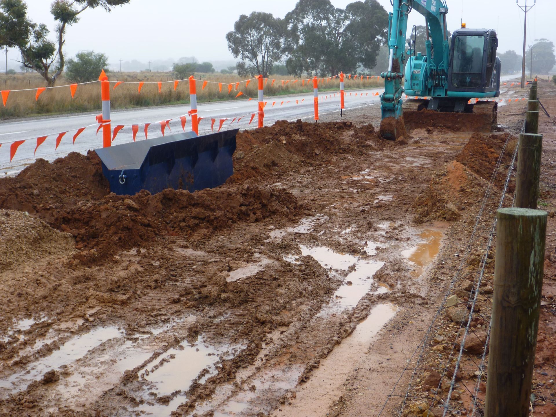 A blue kobelco excavator is working on a muddy road | Murray Bridge, SA | Ridleys SA