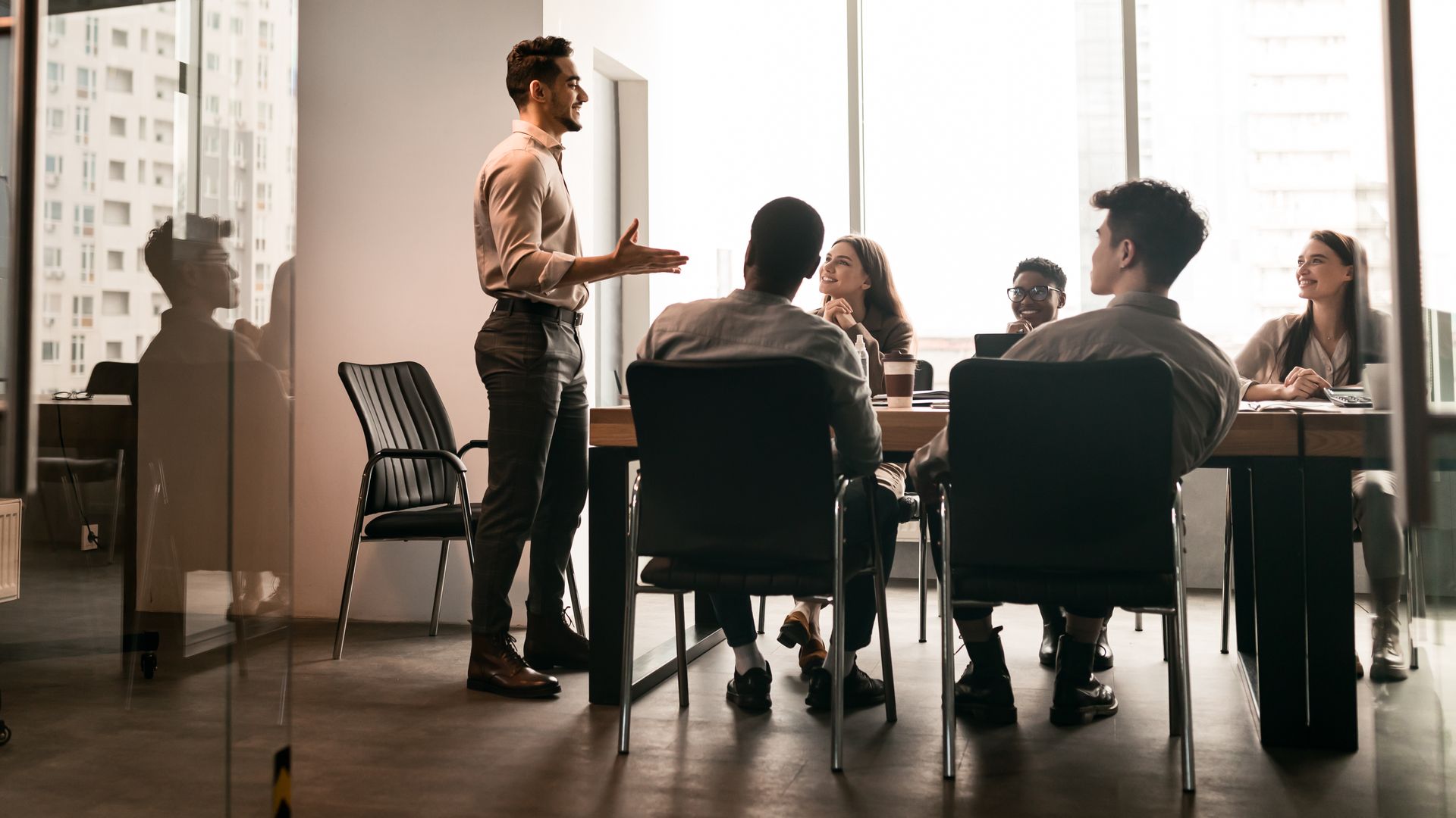 A man is giving a presentation to a group of people sitting at tables in a conference room.