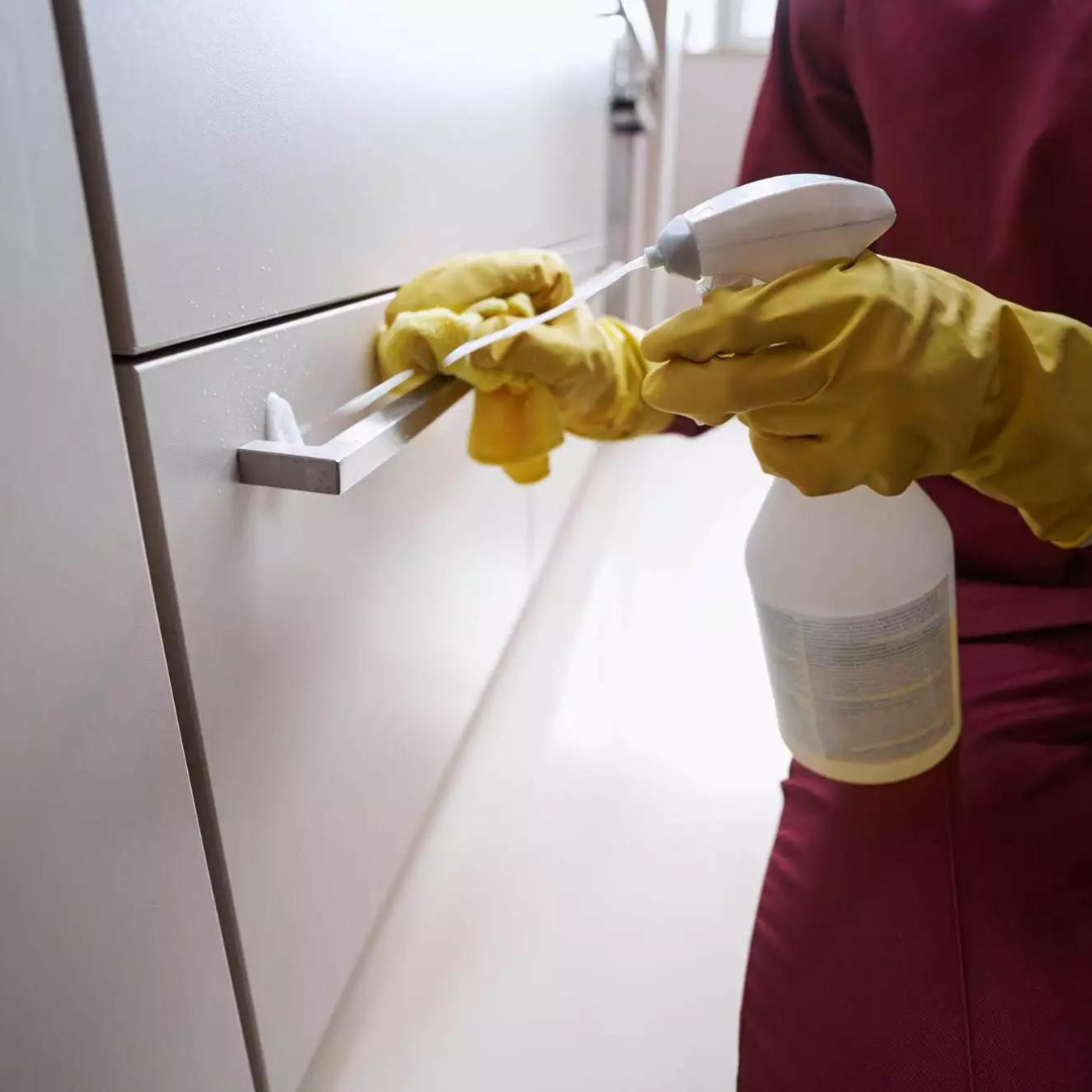 A person wearing yellow gloves is holding a spray bottle