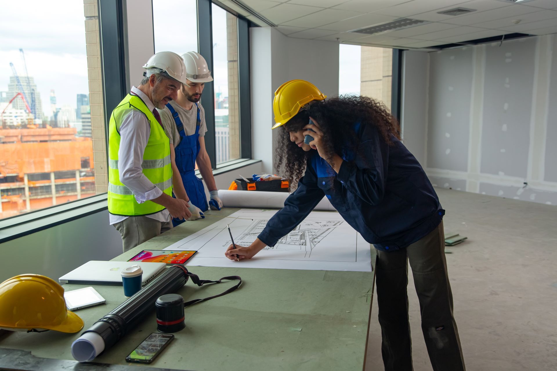 A group of construction workers are standing around a table looking at a blueprint.