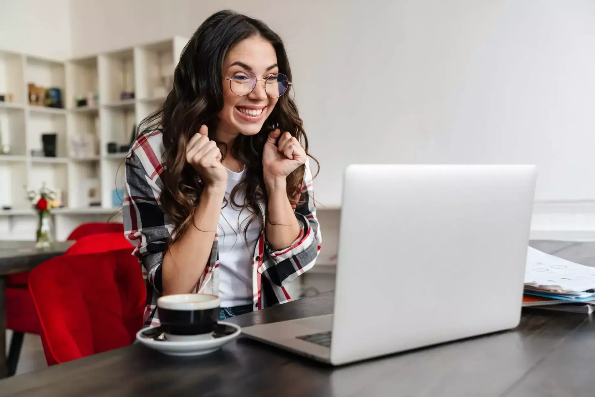 A woman is sitting at a table with a cup of coffee and a laptop computer.