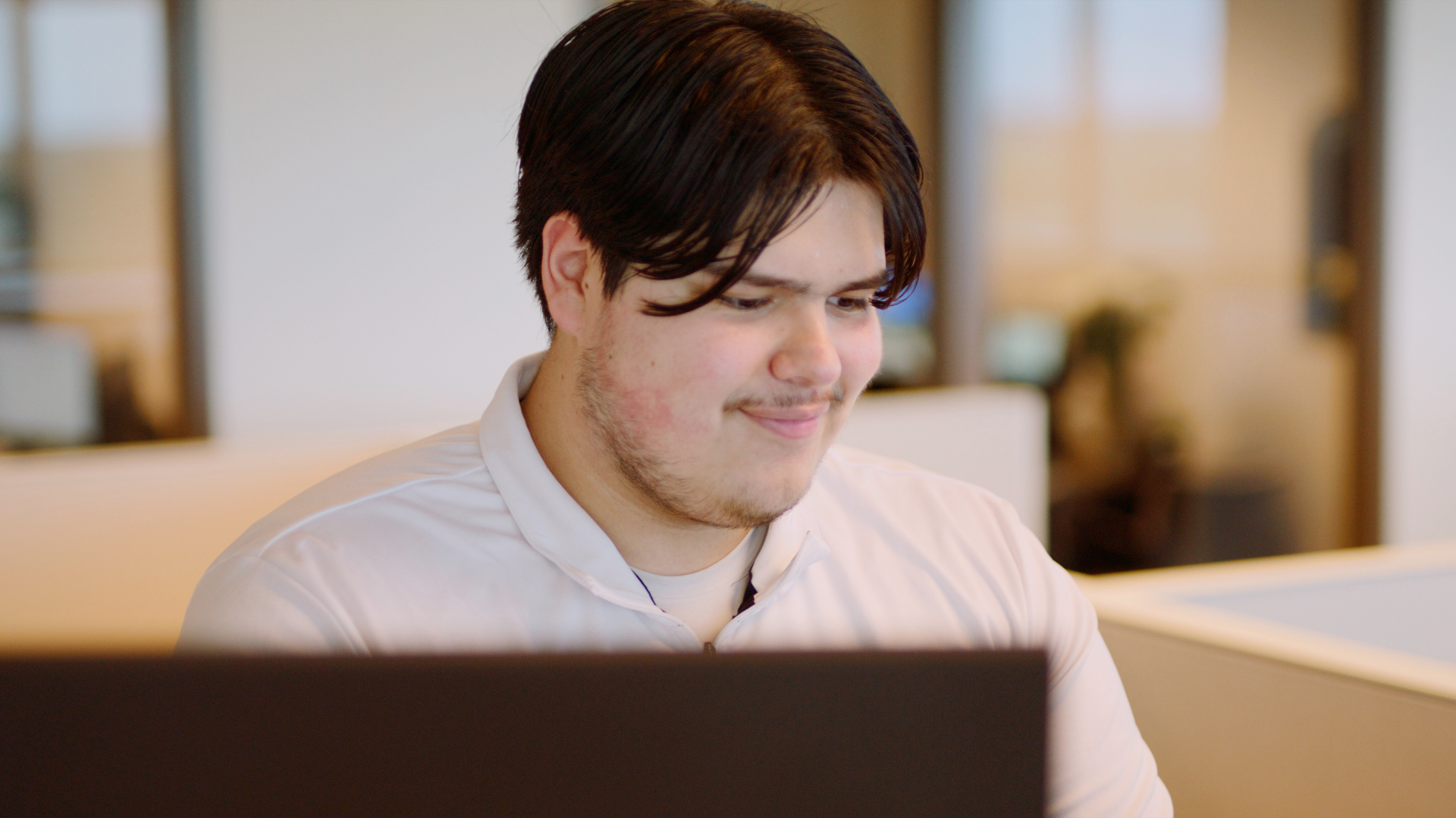 A young man is sitting in front of a laptop computer.