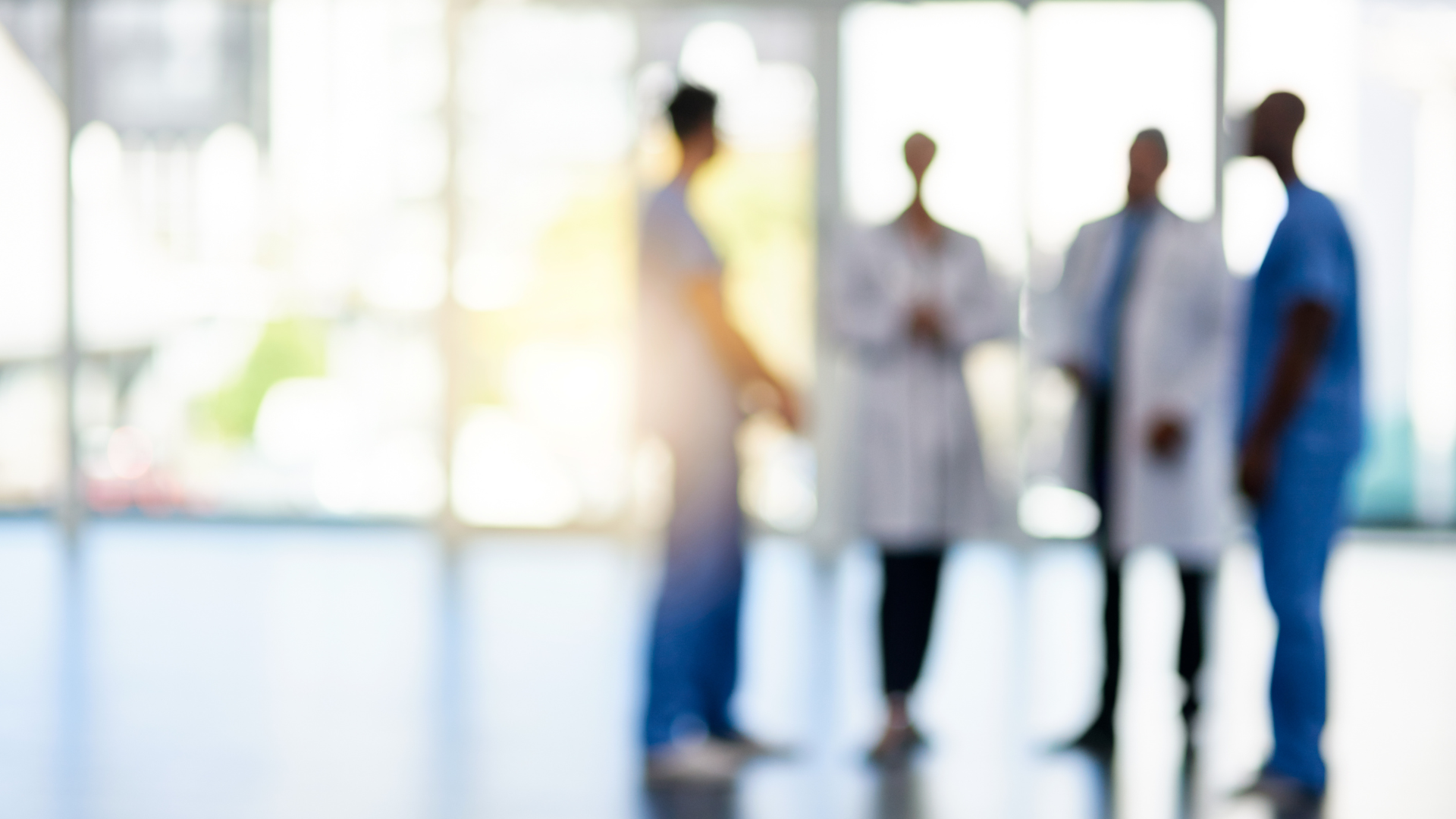 A group of doctors and nurses are standing in a hospital lobby.