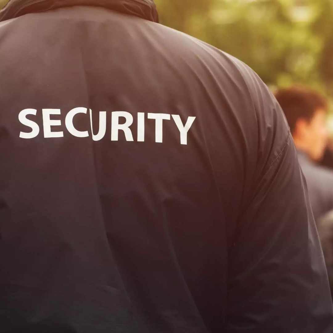 A man wearing a black jacket with the word security on the back