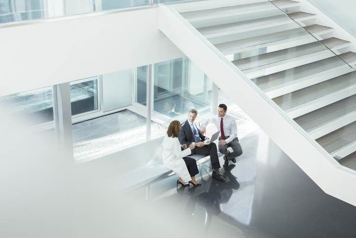 A group of people are sitting on a bench in front of a staircase.