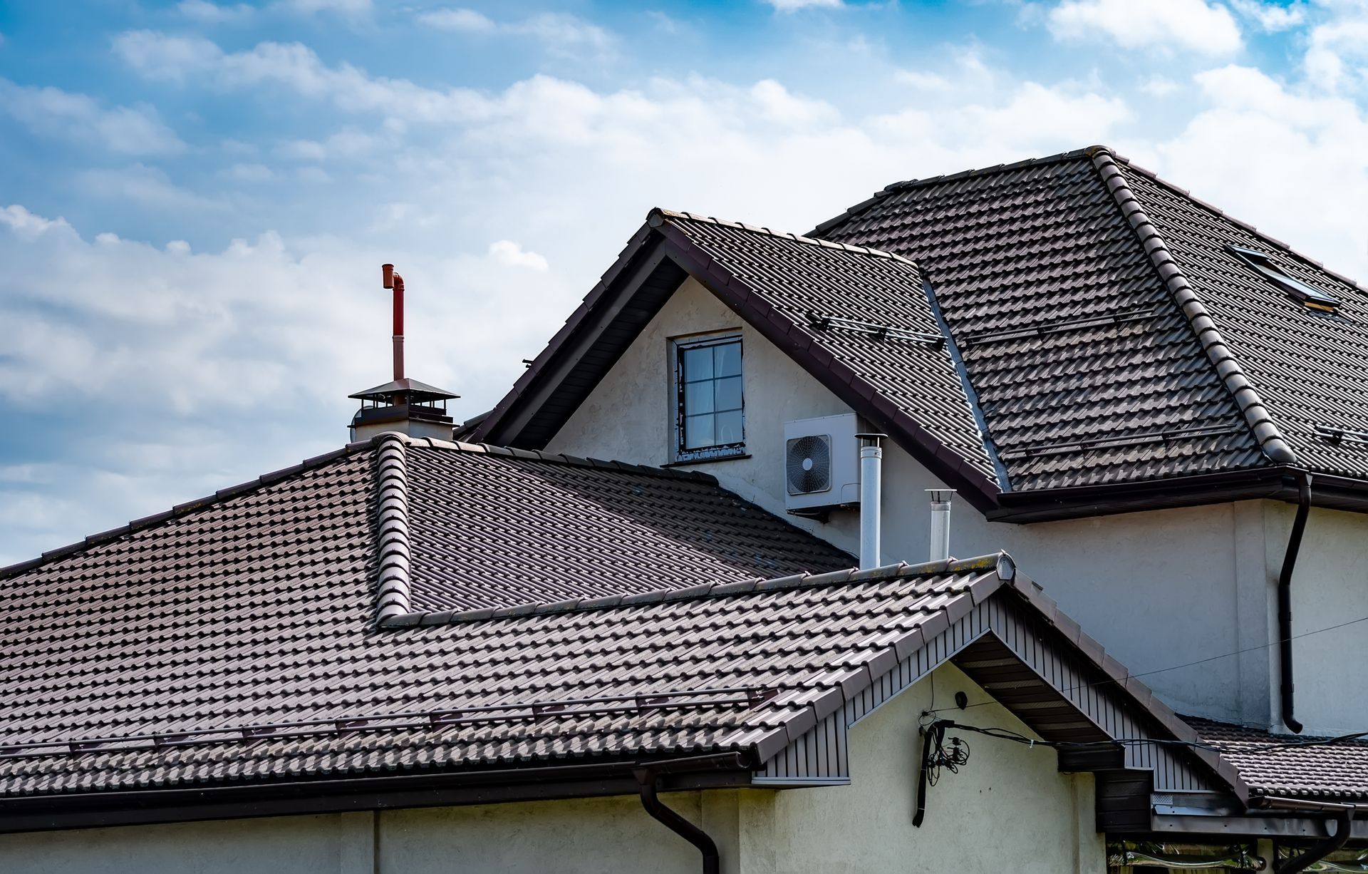 A house with a brown roof and a chimney on top of it.