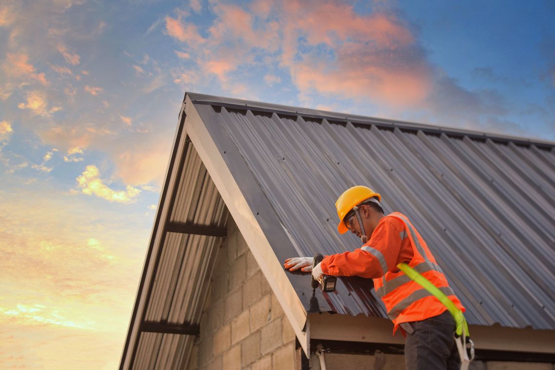 A construction worker is working on the roof of a building.