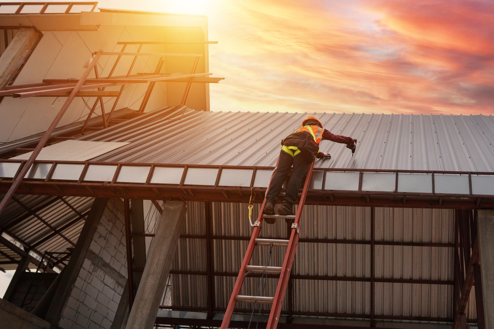 A man is standing on a ladder on top of a metal roof.