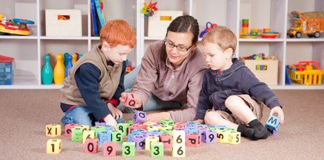 a nursery teacher teaching kids with alphabets and numbers