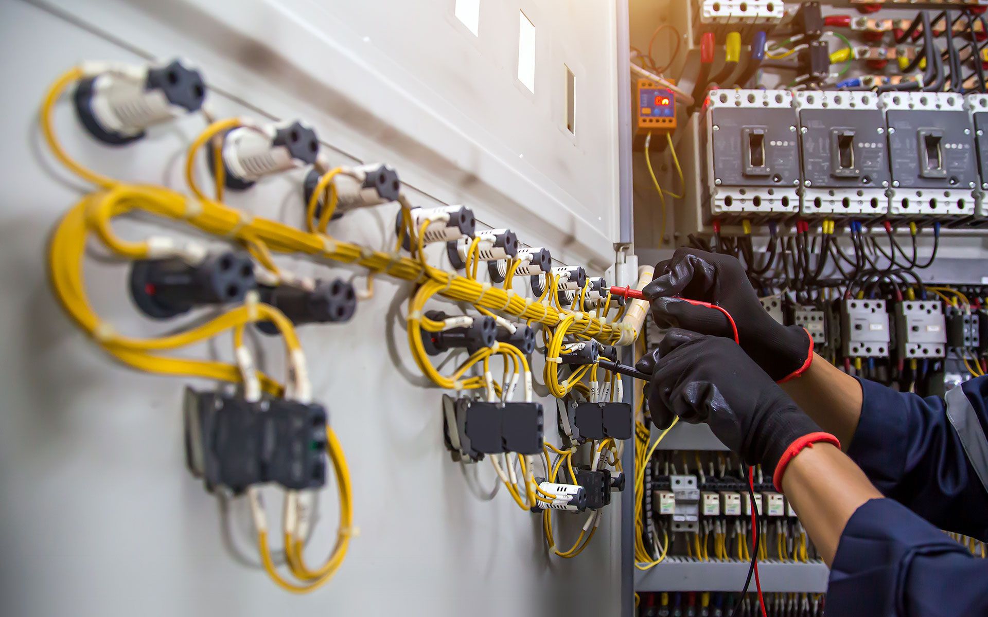A man is working on a electrical panel in a factory.