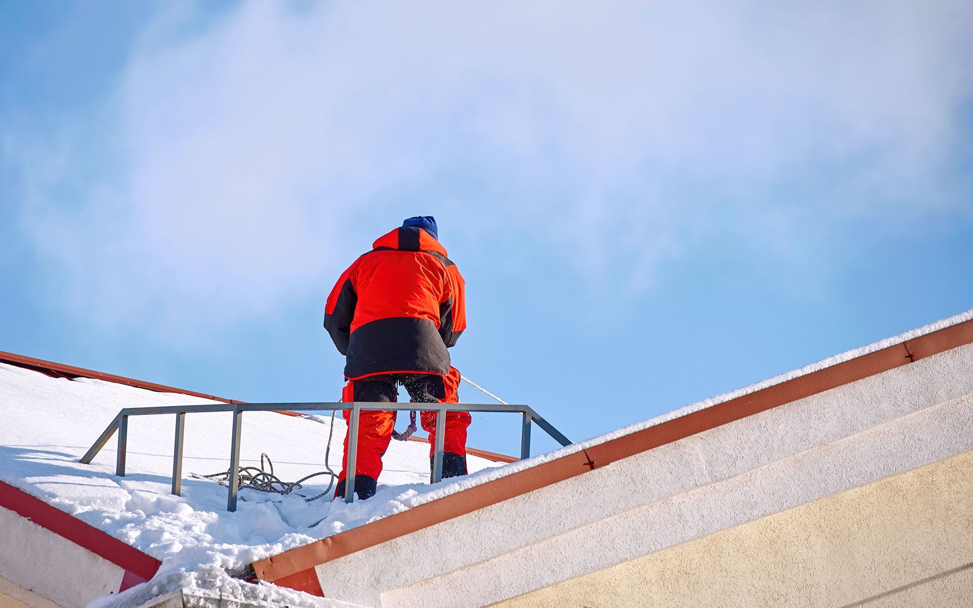 A man is standing on top of a snow covered roof.