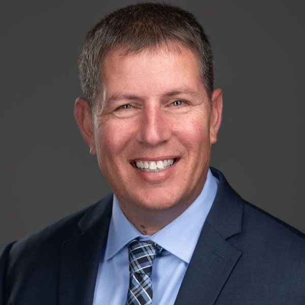 A man in a suit and tie is smiling for the camera.