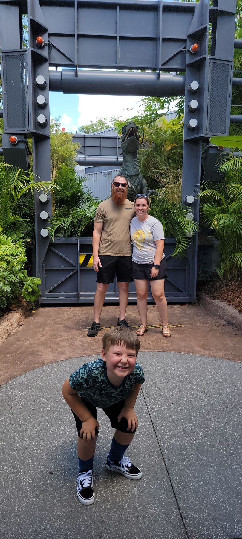 A family is posing for a picture in front of a gate at a theme park.