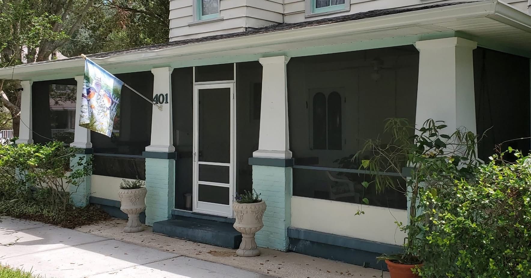 A house with a screened in porch and a flag on it