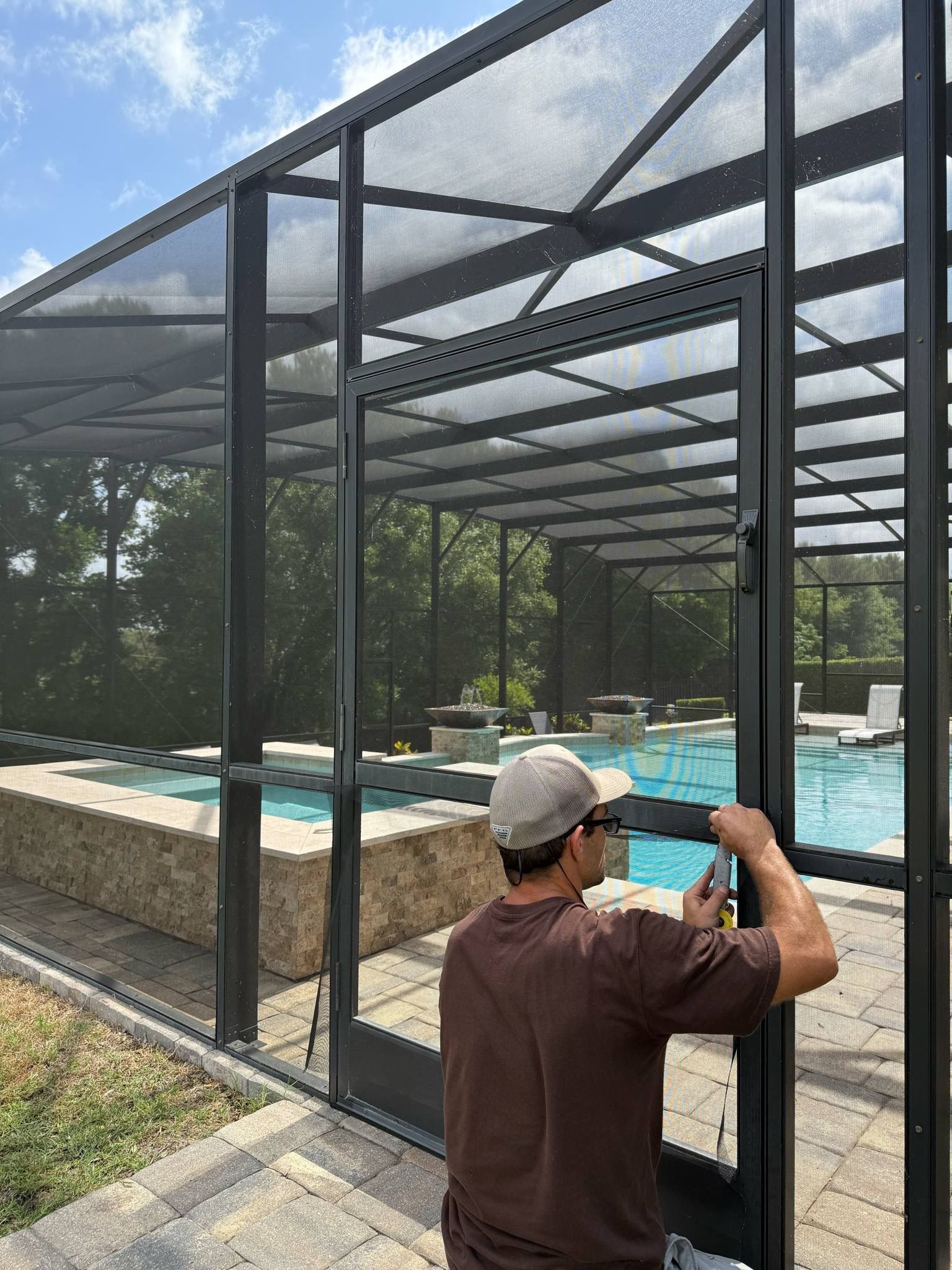A man is working on a screened in swimming pool.