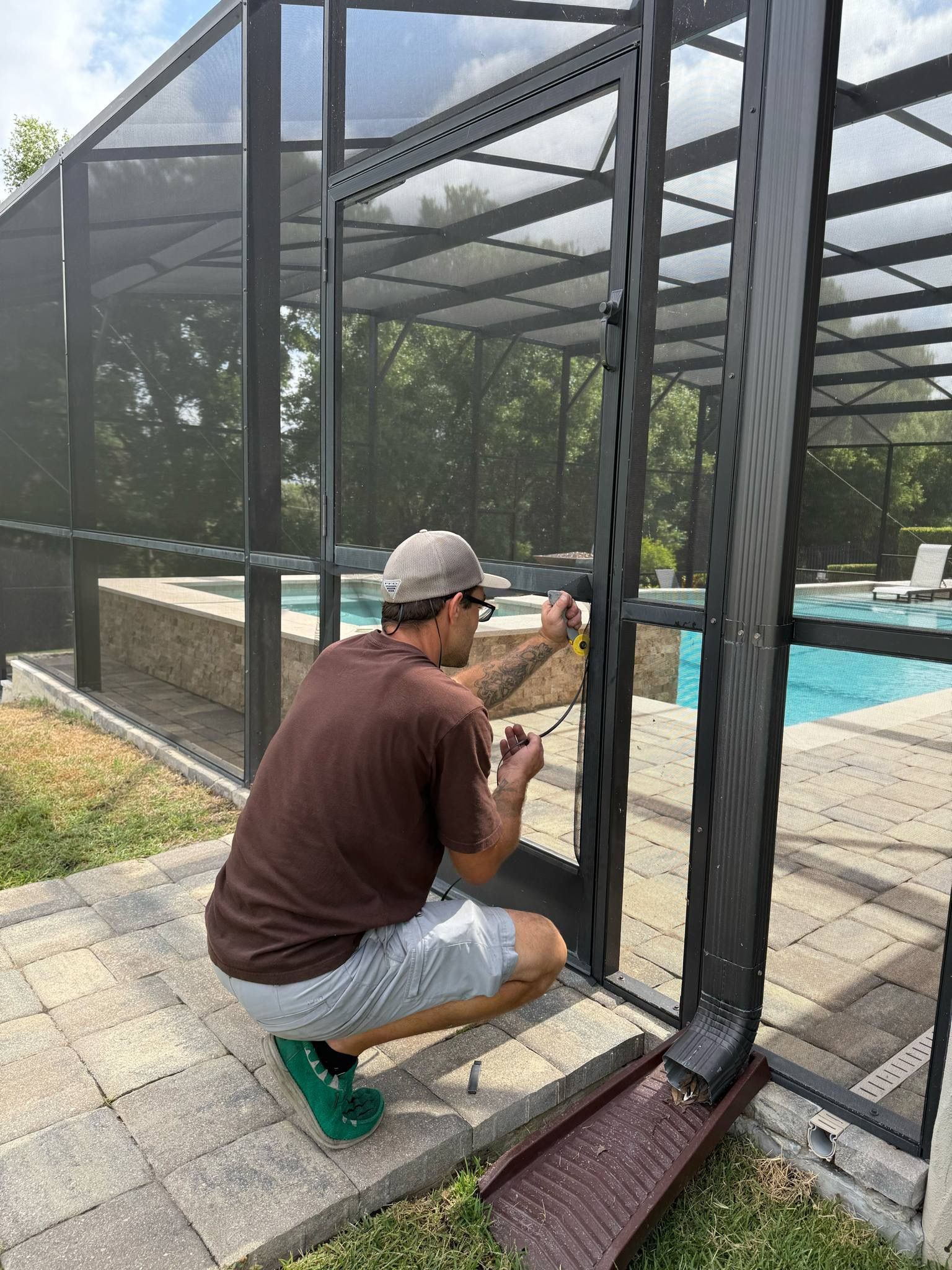 A man is installing a screen door next to a pool.