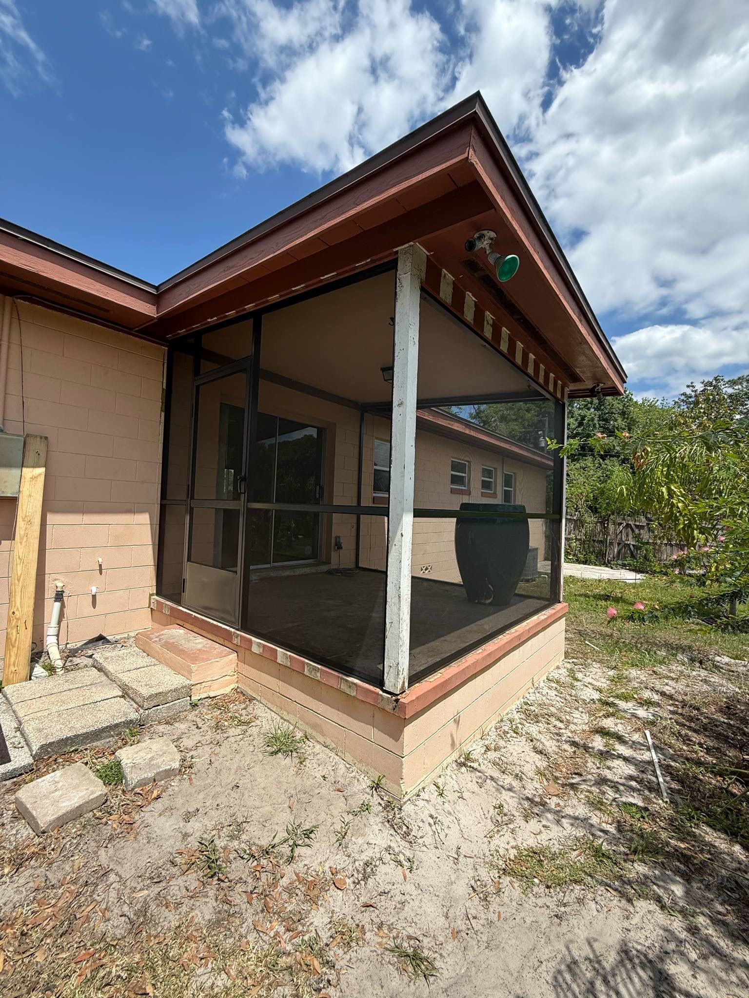 A screened in porch on the side of a house.