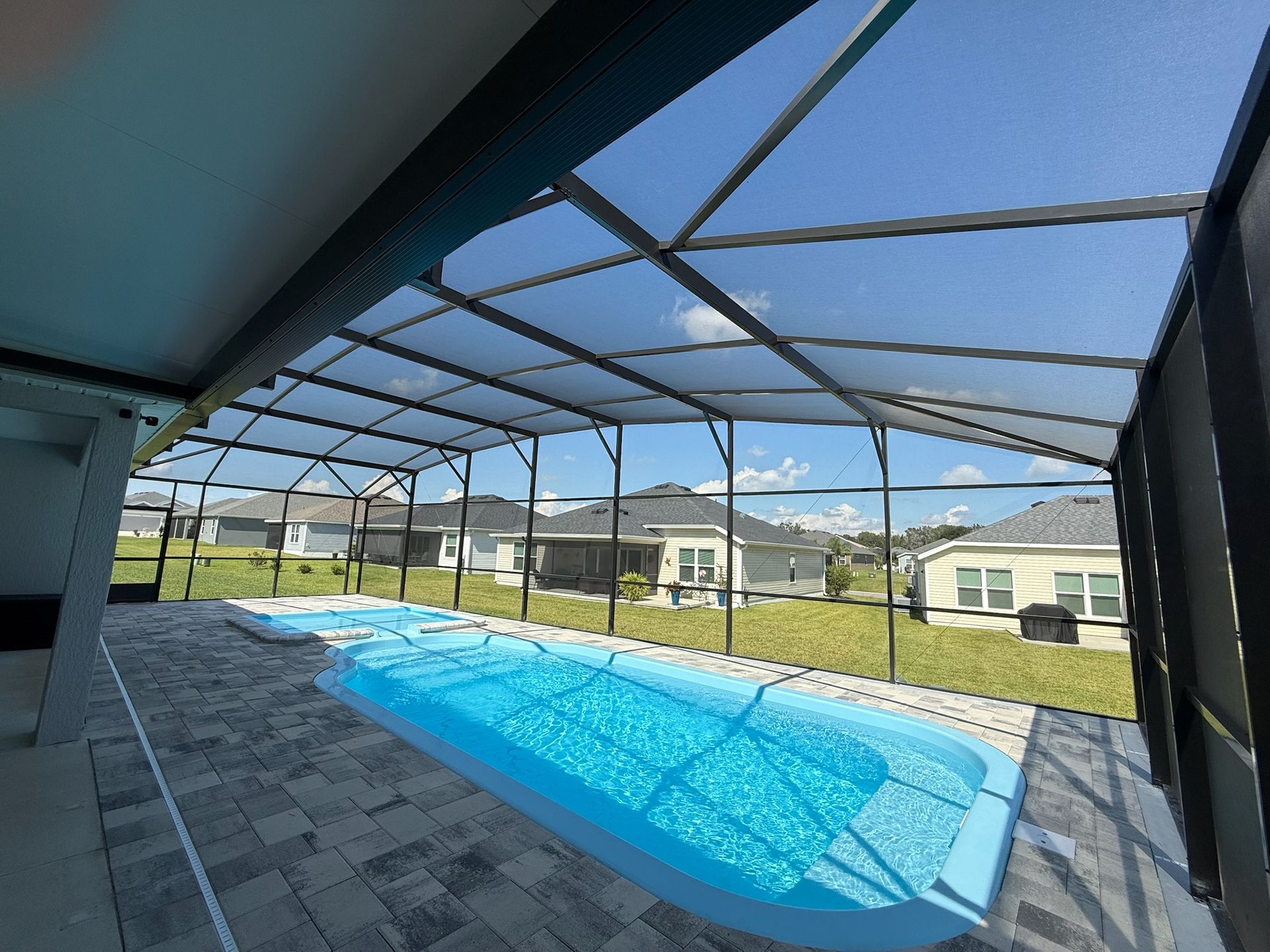 Pool enclosed by a screen structure on a sunny day.
