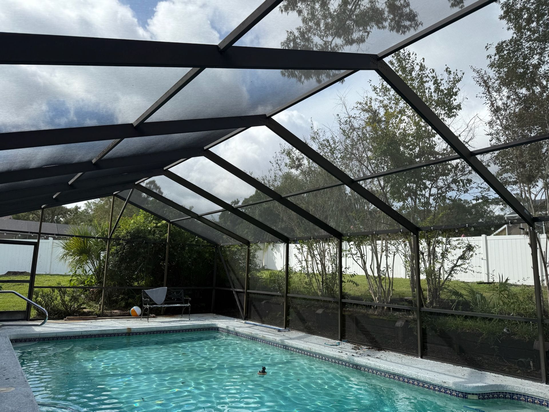 Pool enclosed in black screened structure; sky visible.