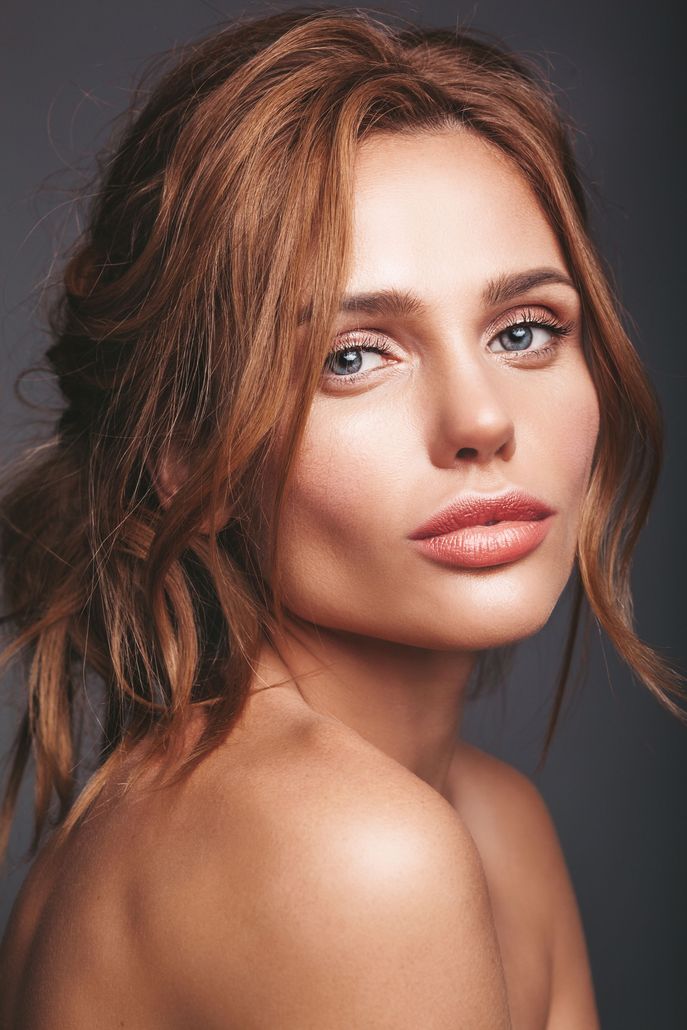 A close up of a woman 's face with her hair in a ponytail.