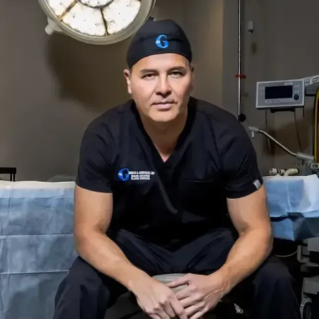 A surgeon is sitting in an operating room wearing a hat with the letter g on it