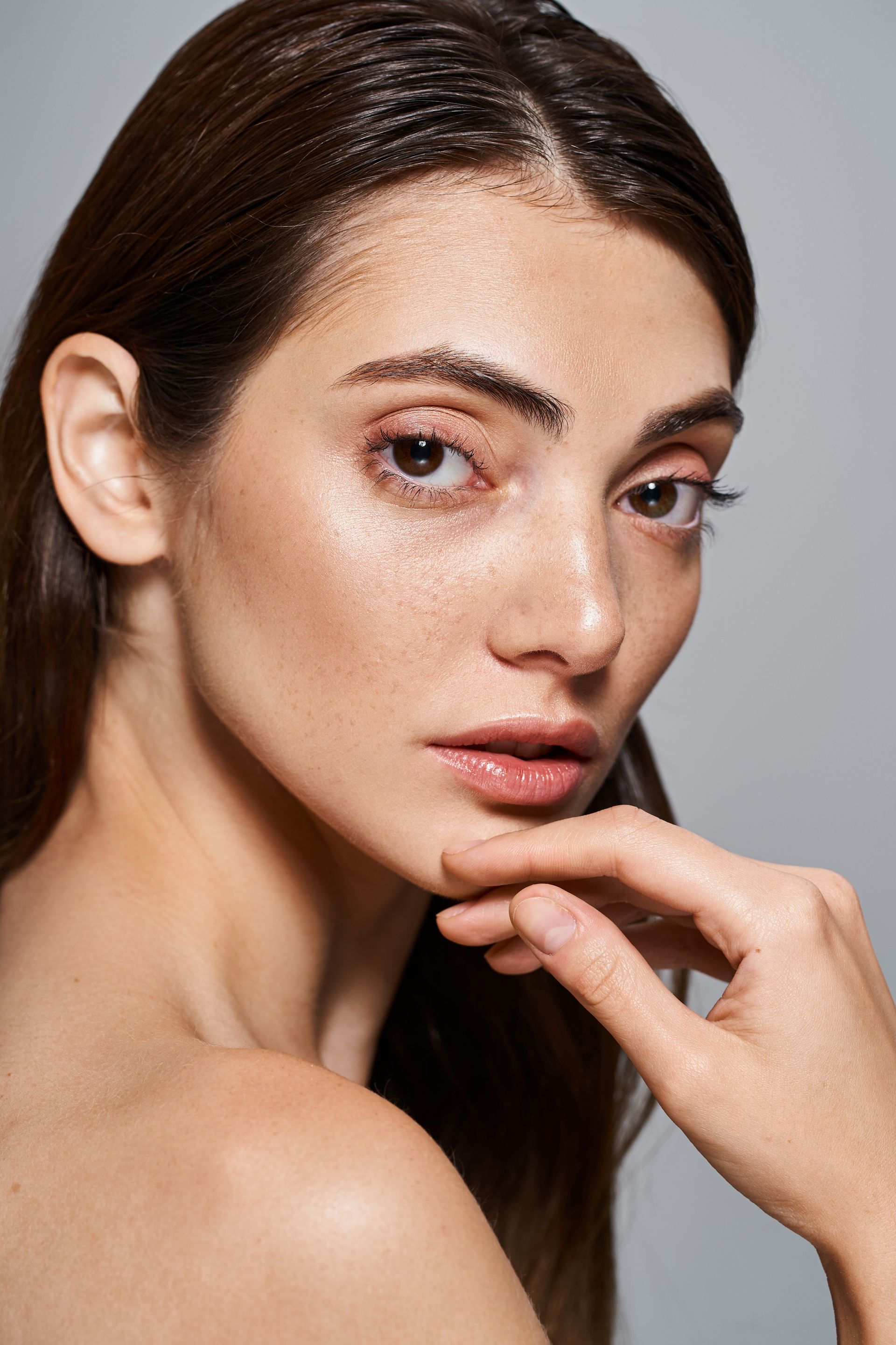 A close up of a woman 's face with her hand on her chin.