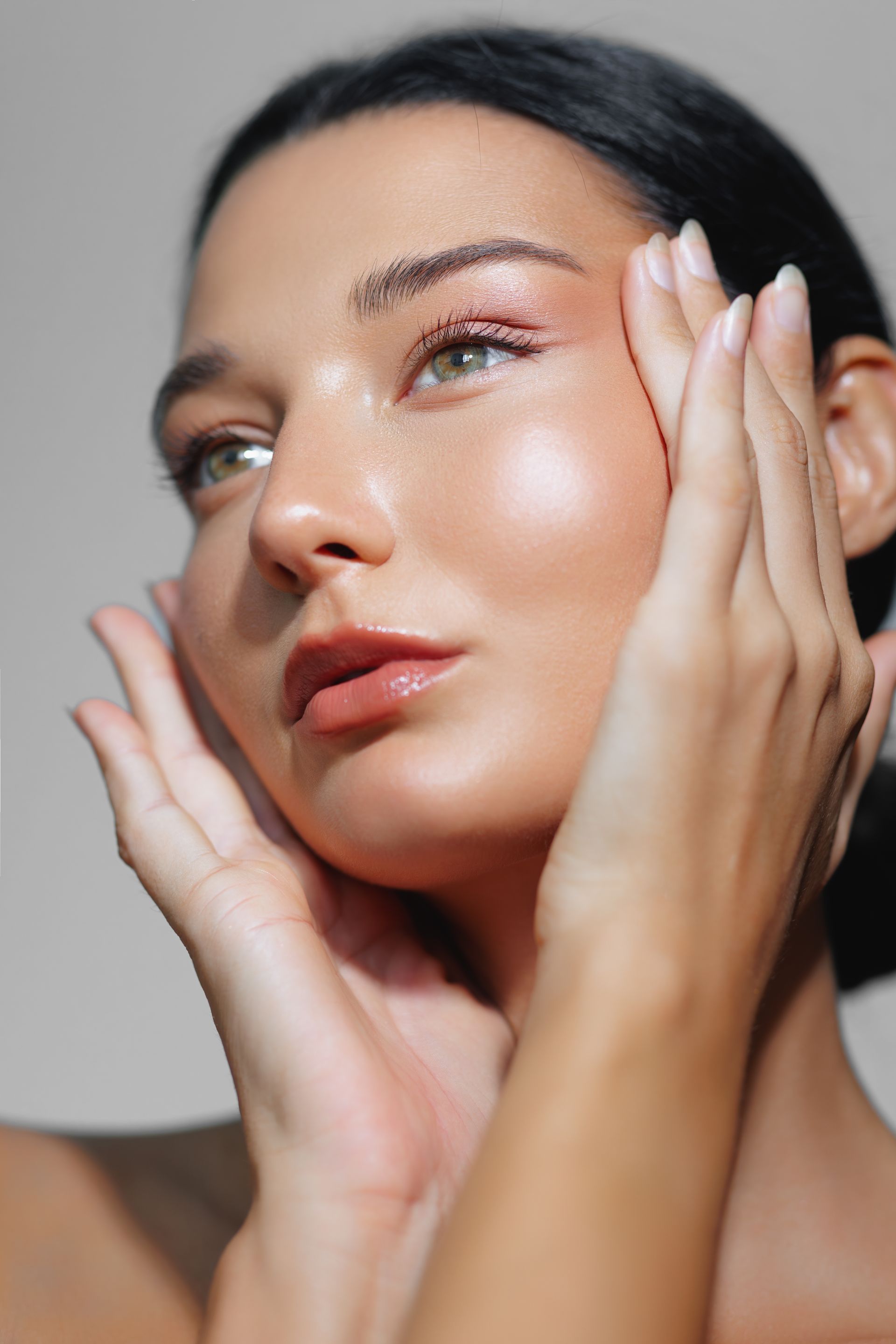 A close up of a woman 's face with her hands on it.