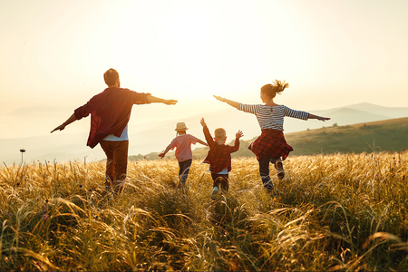 A family running through a field of tall grass at sunset.