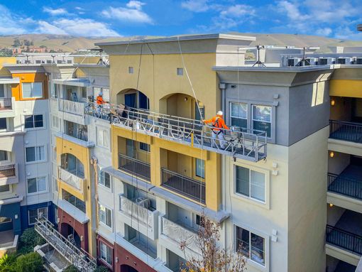 an aerial view of a building being painted with a crane .