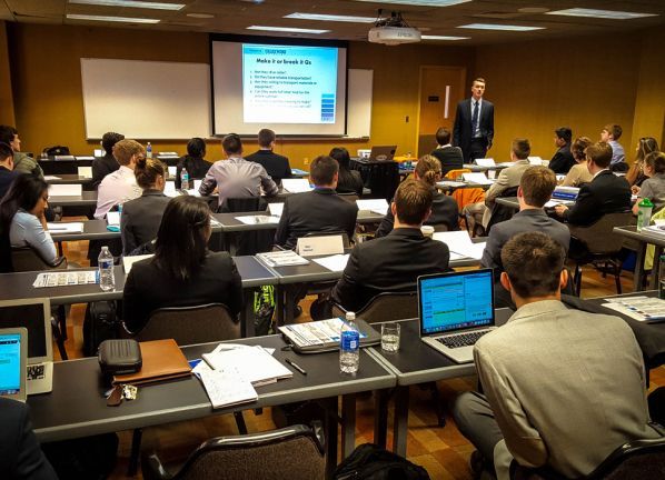 A man is giving a presentation to a group of people in a classroom
