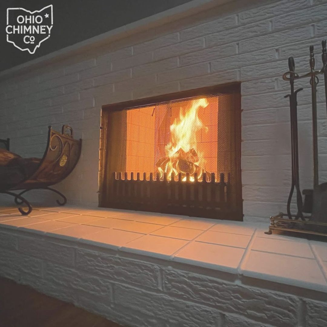 A man is kneeling on top of a roof fixing a chimney.