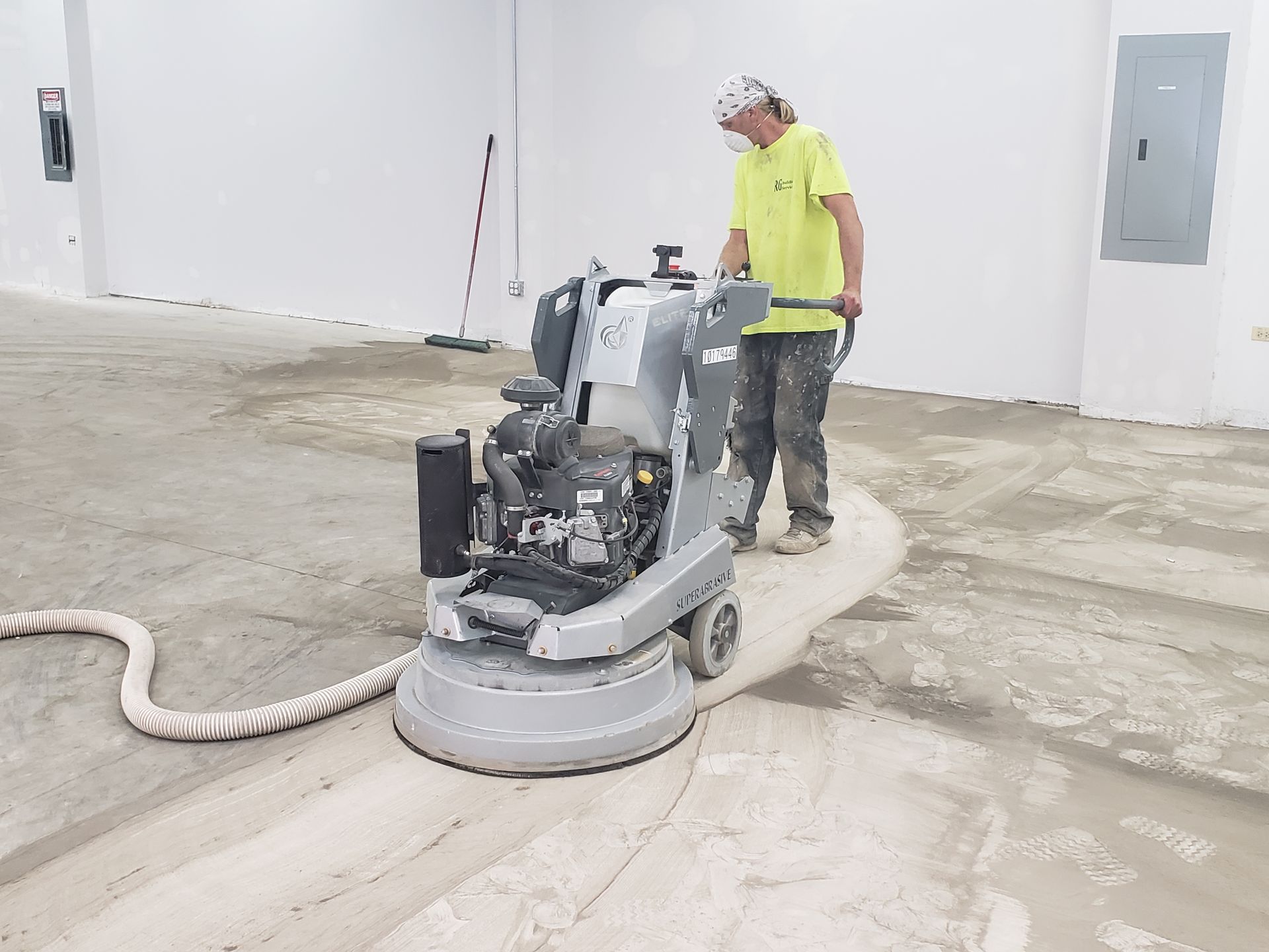 A man is grinding a concrete floor with a machine.