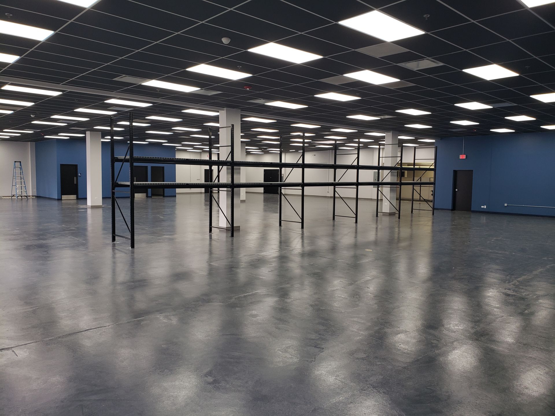 An empty warehouse with lots of shelves and lights on the ceiling