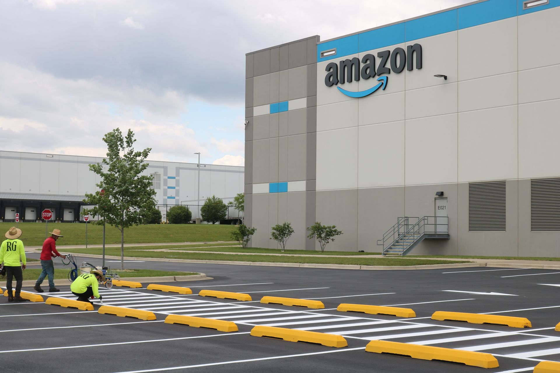 A group of people are painting a crosswalk in front of an amazon building.