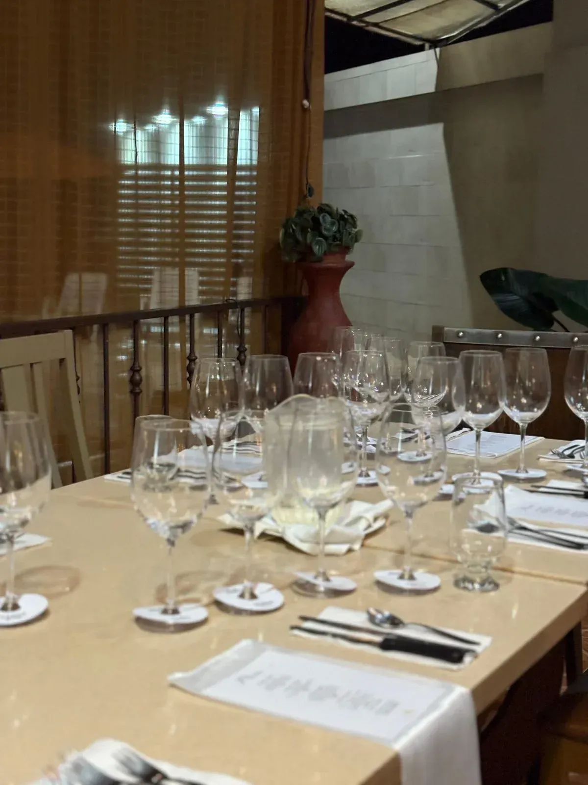 Una mesa puesta para una cena, con vasos, cubiertos y mantelería, en un restaurante.