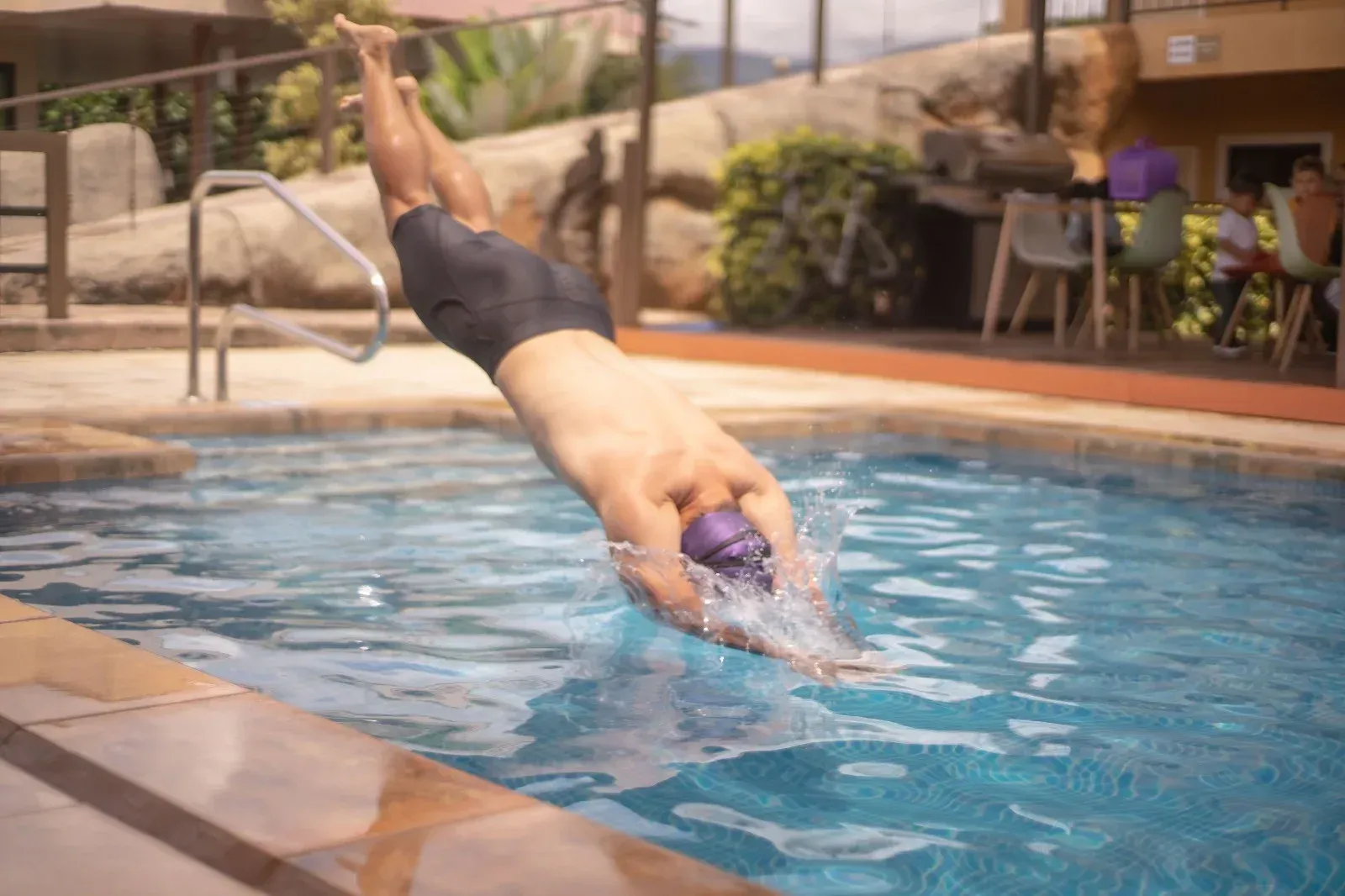 Hombre zambulléndose en una piscina; salpicaduras de agua.