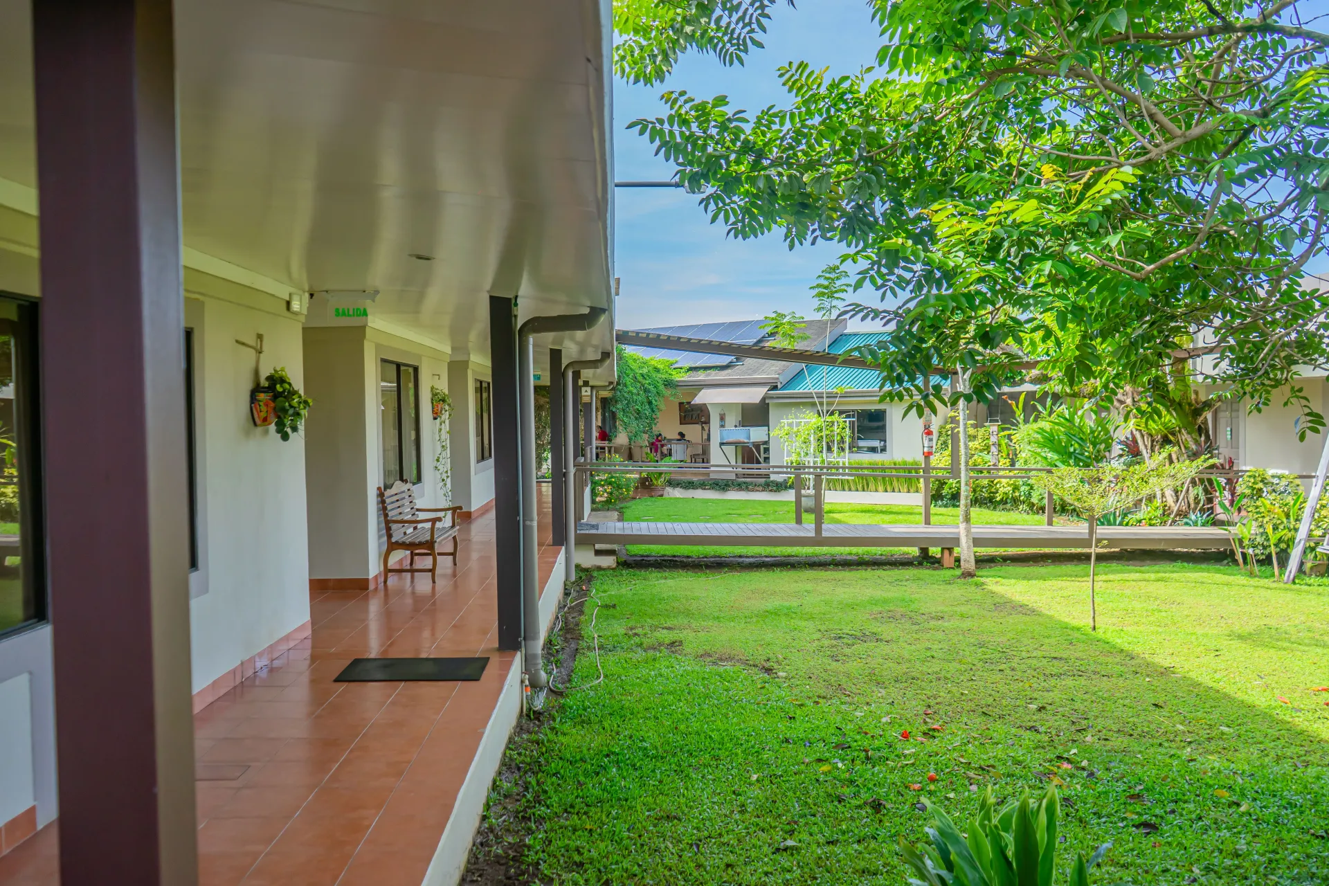 Césped verde exuberante con pasarela cubierta y columnas de soporte marrones.