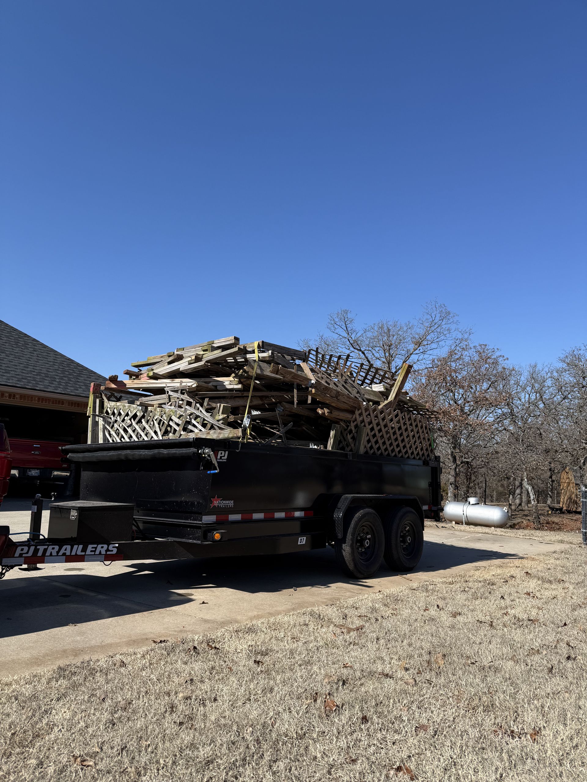 A dump truck is carrying a pile of wood on a trailer.