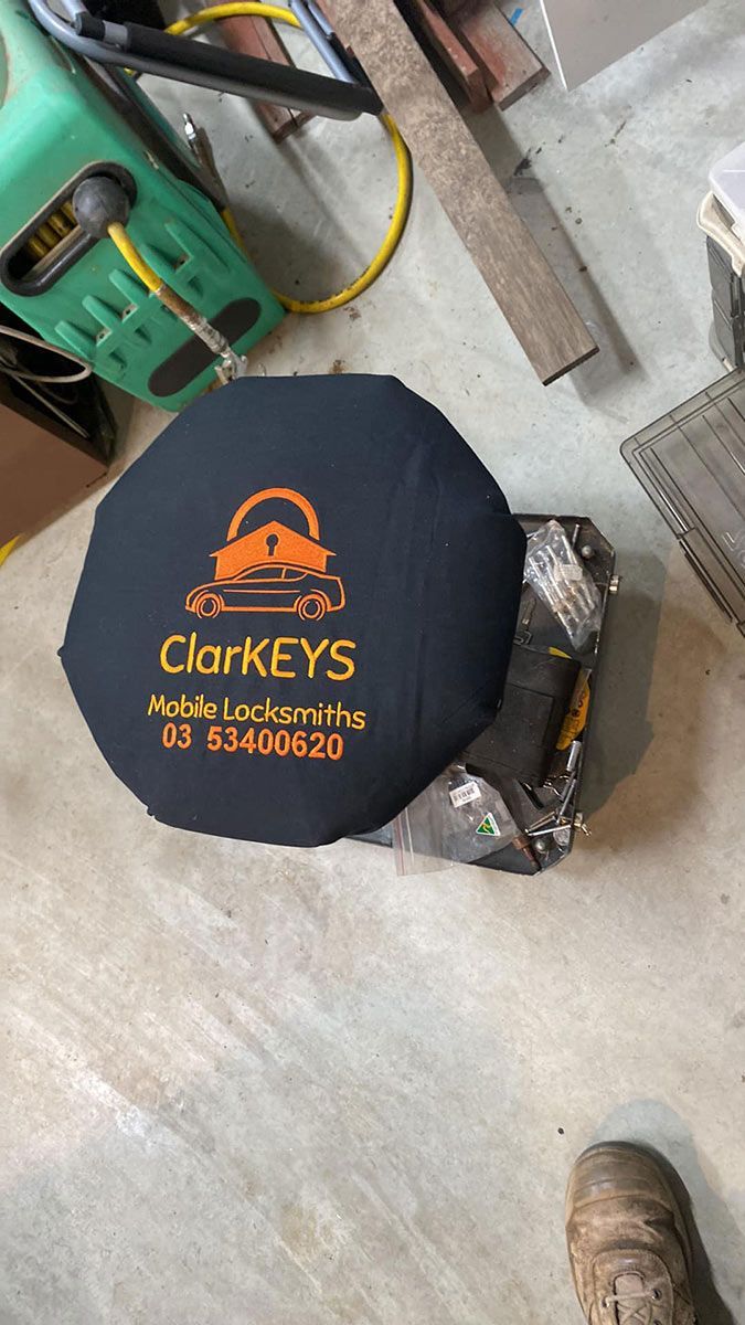 A Person Is Standing Next To A Black Umbrella That Says Clarkeys On It — ClarKEYS Mobile Locksmiths In Winter Valley, VIC