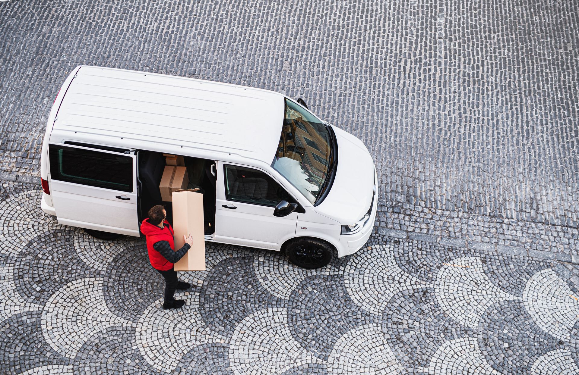 A delivery man is loading a box into a white van.